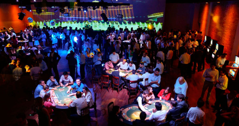 Salão com pessoas e mesas de jogos
