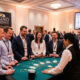 Colaboradores sorrindo e interagindo em uma mesa de jogos de cassino fictício durante festa da firma, exemplificando ativações para eventos corporativos divertidas da Casino Experience.